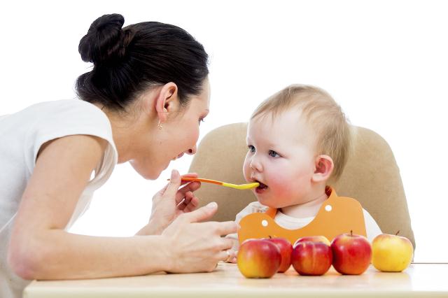 young mother spoon-feeding her baby girl