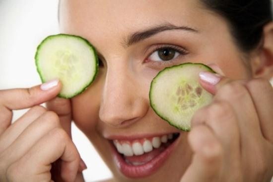 Woman Holding Cucumber Slices over Eyes