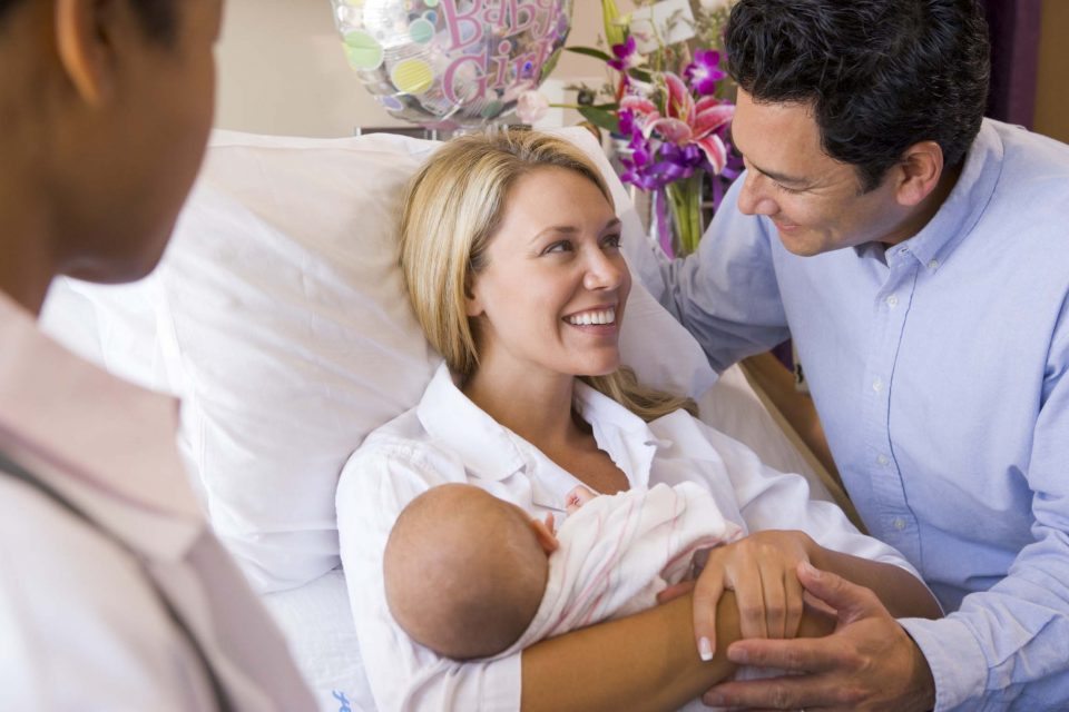 New parents with baby talking to doctor and smiling